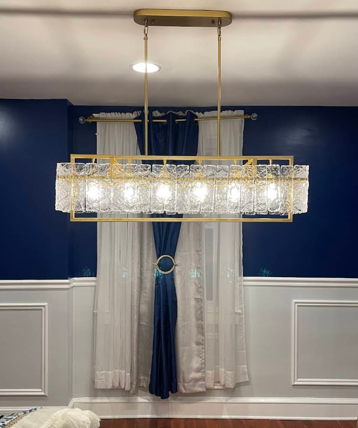 Crystal chandelier installed in a navy blue dining room with wainscoting